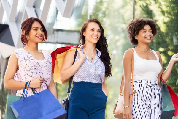 Mulheres felizes com sacos de compras andando na cidade — Fotografia de Stock