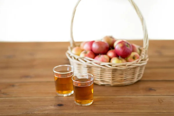 Äpfel im Korb und Saftgläser auf dem Tisch — Stockfoto