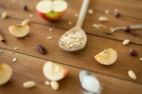 Farina d'avena in cucchiaio di legno, mele e noci tagliate — Foto Stock