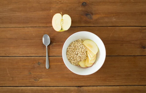 Havregryn i skål med äpple och sked på bordet — Stockfoto