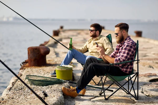 Vänner med smartphone och öl fiske på piren — Stockfoto