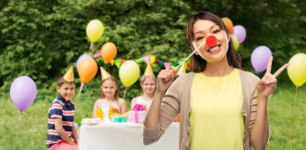 Frau mit Clownsnase bei Kindergeburtstag Stockbild