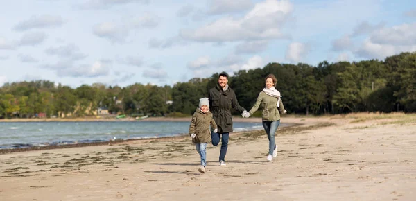 Famiglia felice che corre lungo la spiaggia autunnale — Foto Stock
