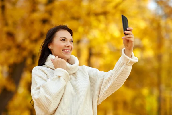 Woman taking selfie by smartphone at autumn park — Stock Photo, Image