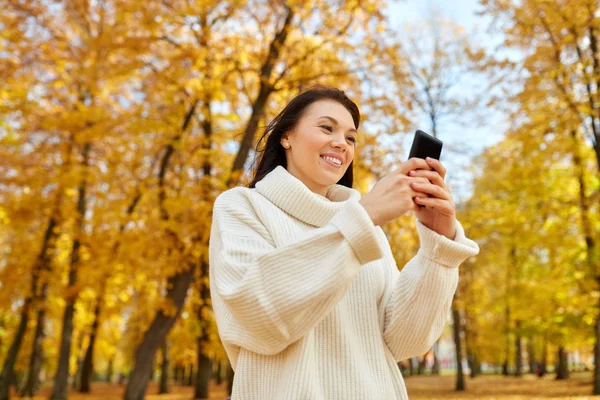 秋の公園にスマートフォンを持つ女性 — ストック写真