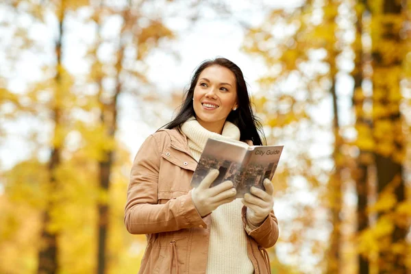 Glückliche junge Frau mit Stadtführer im Herbstpark — Stockfoto