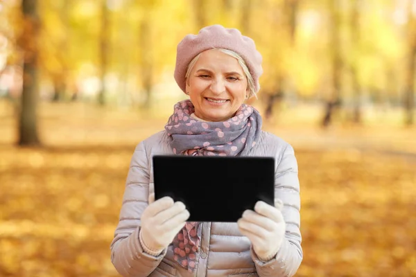 Ανώτερη γυναίκα με tablet υπολογιστή στο φθινοπωρινό πάρκο — Φωτογραφία Αρχείου