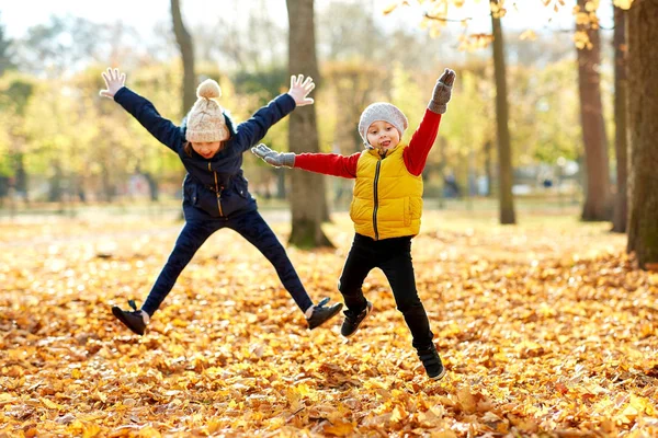 Happy children running at autumn park — Stock Photo, Image