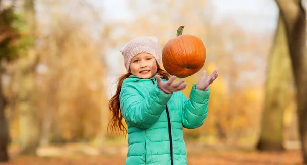 Happy girl playing with pumpkin at autumn park — Stock Photo, Image