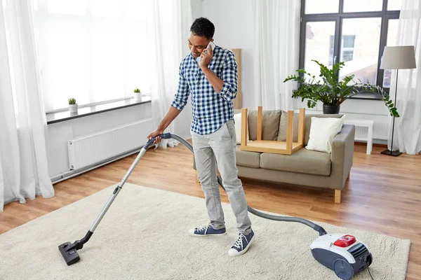 Homme avec aspirateur appelant sur la cellule à la maison — Photo