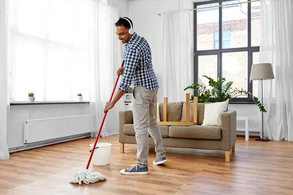 Evde paspas Temizleme zemin ile kulaklık adam — Stok fotoğraf