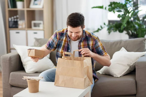 Улыбающийся мужчина распаковывает еду на вынос дома — стоковое фото