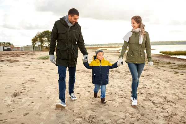 Família feliz andando ao longo da praia de outono Imagem De Stock