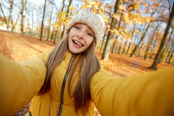 快乐的女孩在秋天的公园里自拍 免版税图库图片