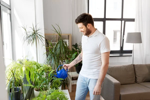 Чоловік поливає домашні рослини вдома — стокове фото