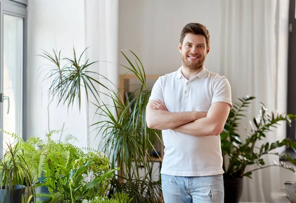 Uomo sorridente con piante d'appartamento a casa — Foto Stock