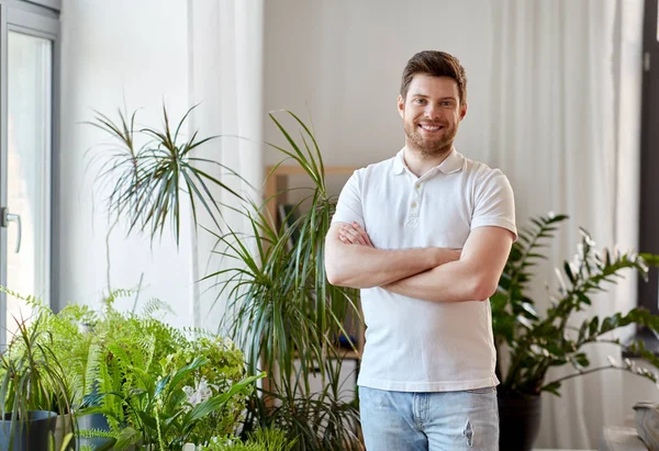 Hombre sonriente con plantas de interior en casa — Foto de Stock