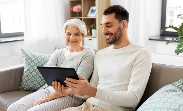 Old mother and adult son with tablet pc at home — Stock Photo, Image