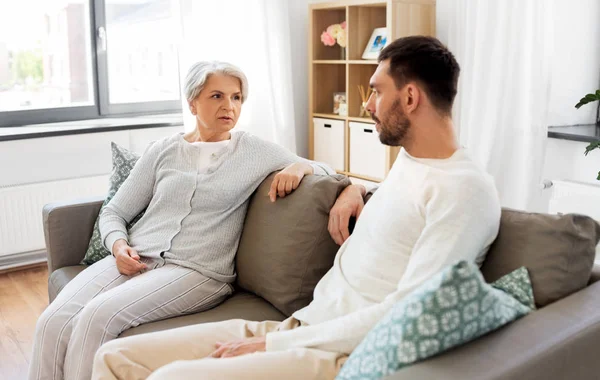 Madre mayor hablando con hijo adulto en casa —  Fotos de Stock