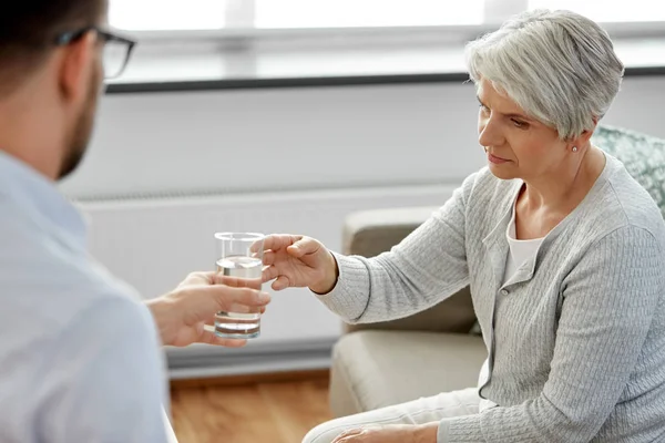 Psicólogo dando vaso de agua a la mujer mayor — Foto de Stock