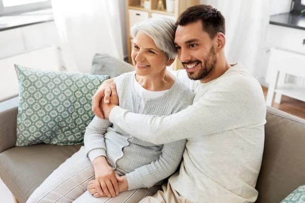 Senior moeder met volwassen zoon knuffelen thuis — Stockfoto