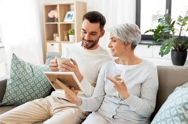 Figlio adulto e madre anziana con foto a casa — Foto Stock