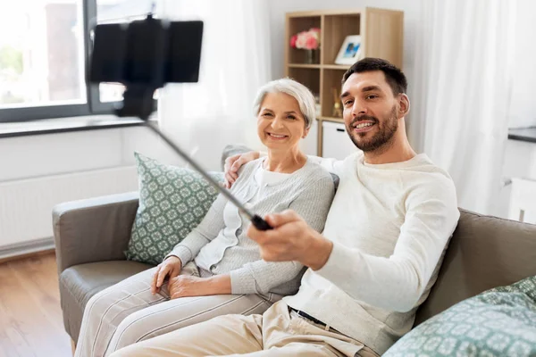 Senior mother with adult son taking selfie at home — Stock Photo, Image