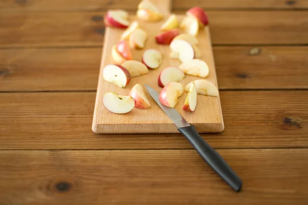 Tranches de pommes et couteau sur planche à découper en bois — Photo