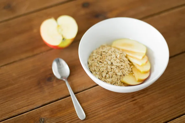 Oatmeal dalam mangkuk dengan apel dan sendok di atas meja — Stok Foto