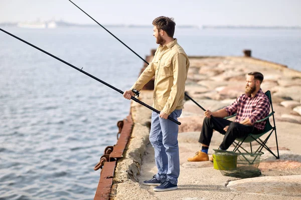 Amigos felizes com varas de pesca no cais — Fotografia de Stock