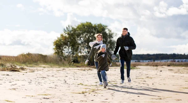 Famiglia felice che corre lungo la spiaggia autunnale — Foto Stock