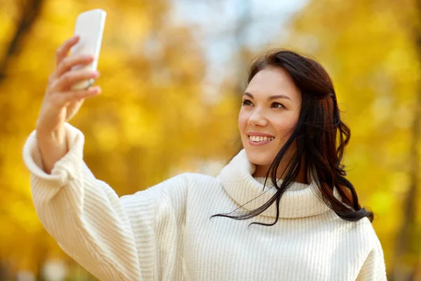 Woman taking selfie by smartphone at autumn park — Stock Photo, Image