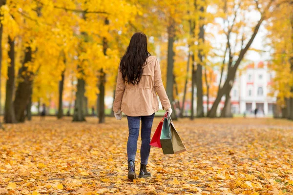 Frau mit Einkaufstüten spaziert durch Herbstpark — Stockfoto