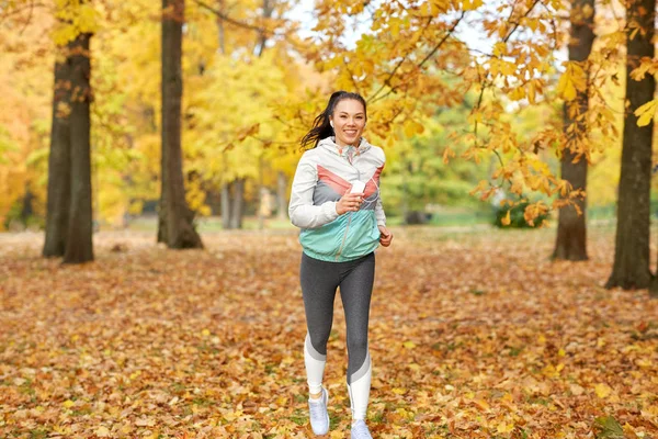 Femme courant dans le parc et écoutant de la musique — Photo