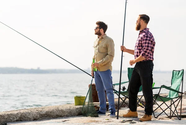 Amigos do sexo masculino com varas de pesca e cerveja no cais — Fotografia de Stock