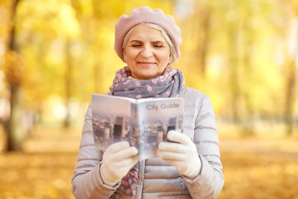 Sonbahar parkında şehir rehberiyle yaşlı bir kadın. — Stok fotoğraf
