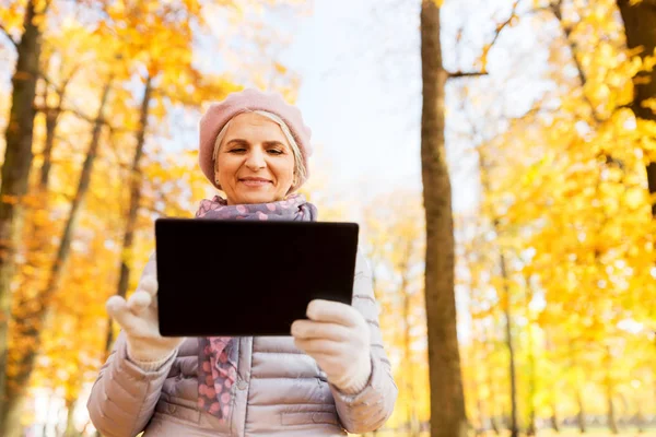 Mulher sênior com tablet pc no parque de verão — Fotografia de Stock