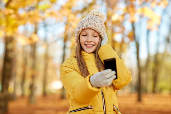 Dziewczyna biorąc selfie przez smartfona w jesiennym parku — Zdjęcie stockowe