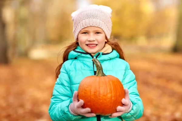 Happy redhead girl with pumpkin at autumn park — Stock Photo, Image