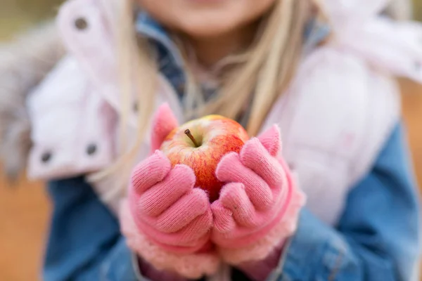 Nahaufnahme eines kleinen Mädchens, das im Herbst einen Apfel hält — Stockfoto
