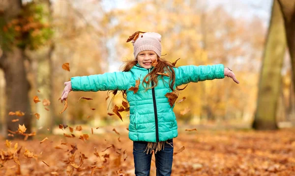 Ragazza felice che gioca con le foglie al parco autunnale — Foto Stock