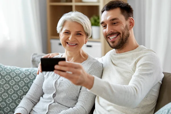 Seniorin mit erwachsenem Sohn macht Selfie zu Hause — Stockfoto