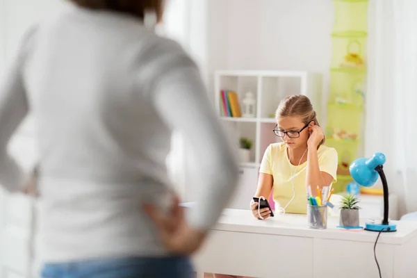 Girl listening to music and mother entering room — Stock Photo, Image