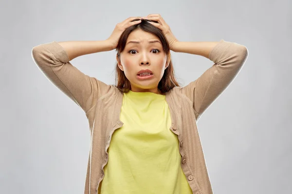 terrified asian woman holding to her head