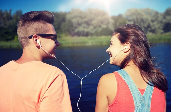 Feliz casal adolescente com fones de ouvido no cais do rio — Fotografia de Stock