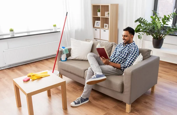 Hombre leyendo libro y descansando después de la limpieza del hogar — Foto de Stock