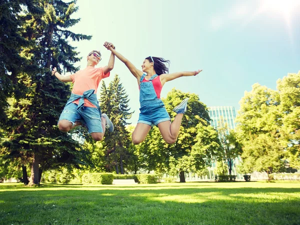 Šťastný dospívající pár jumping v letním parku — Stock fotografie