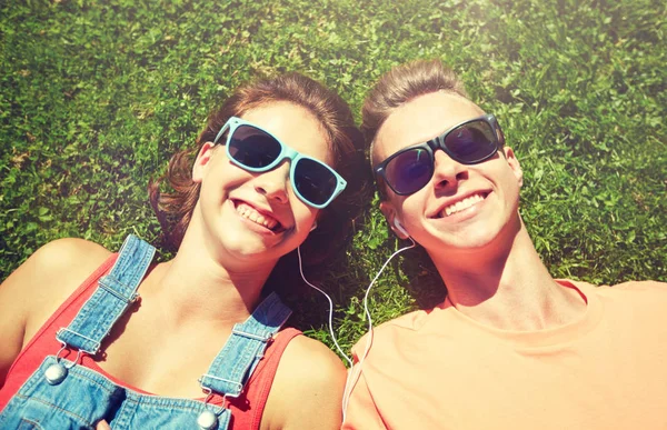 Feliz pareja adolescente con auriculares tumbados en la hierba —  Fotos de Stock