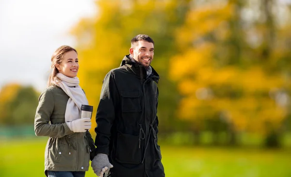 Pareja con vaso caminando a lo largo del parque de otoño —  Fotos de Stock