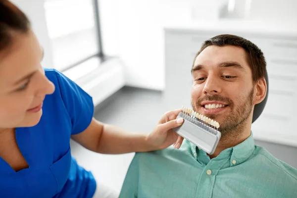Dentista elegir el color del diente para el paciente en la clínica —  Fotos de Stock